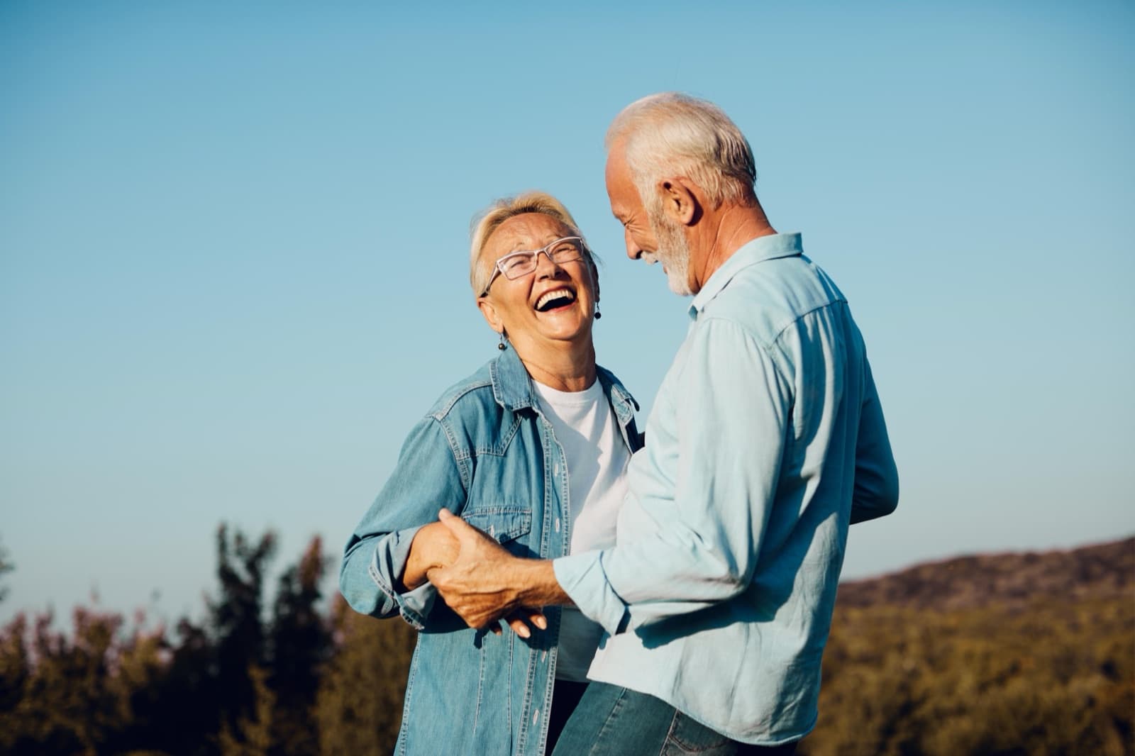 A happy, active senior couple laughing together outdoors
