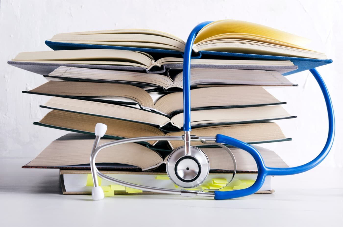 A stack of open books with a stethoscope draped across them